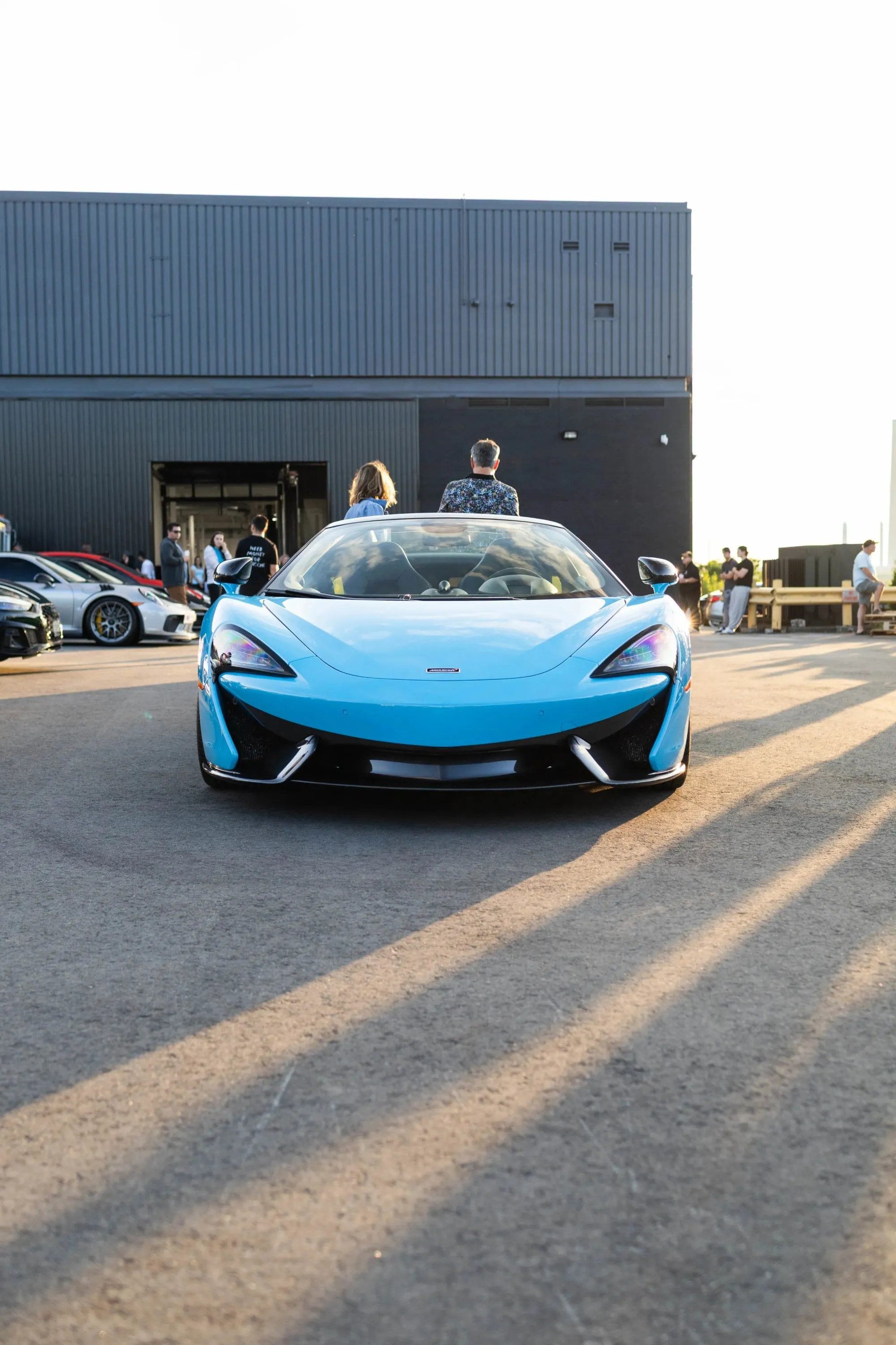 A blue Mclaren dazzles car-show guests in the late afternoon sunshine.