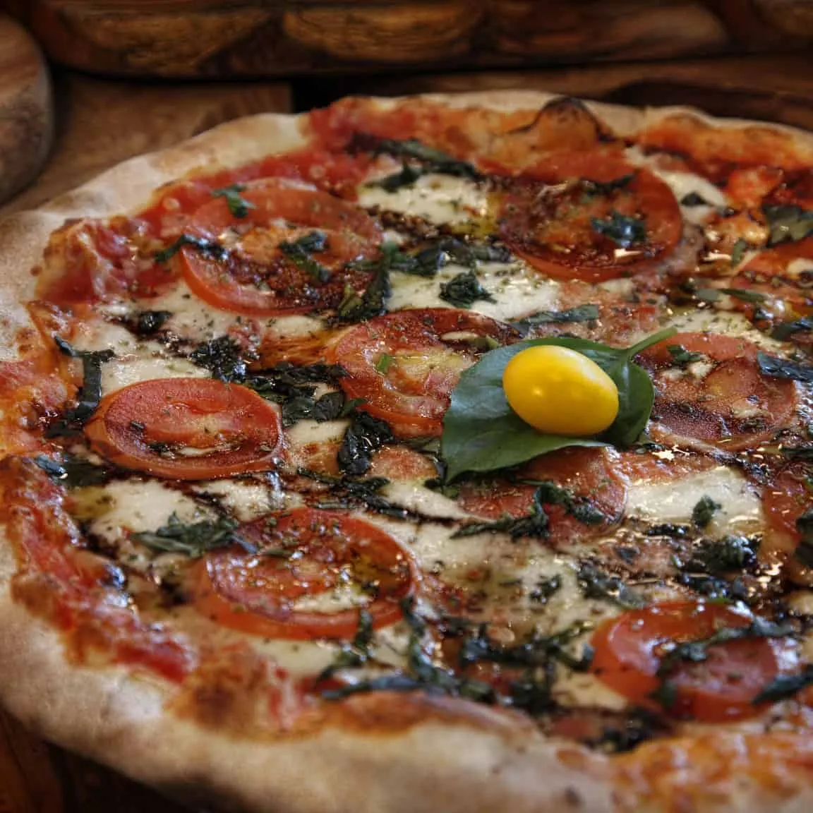 A close-up of a traditional style pizza with a perfectly charred crust and fresh basil leaves on top