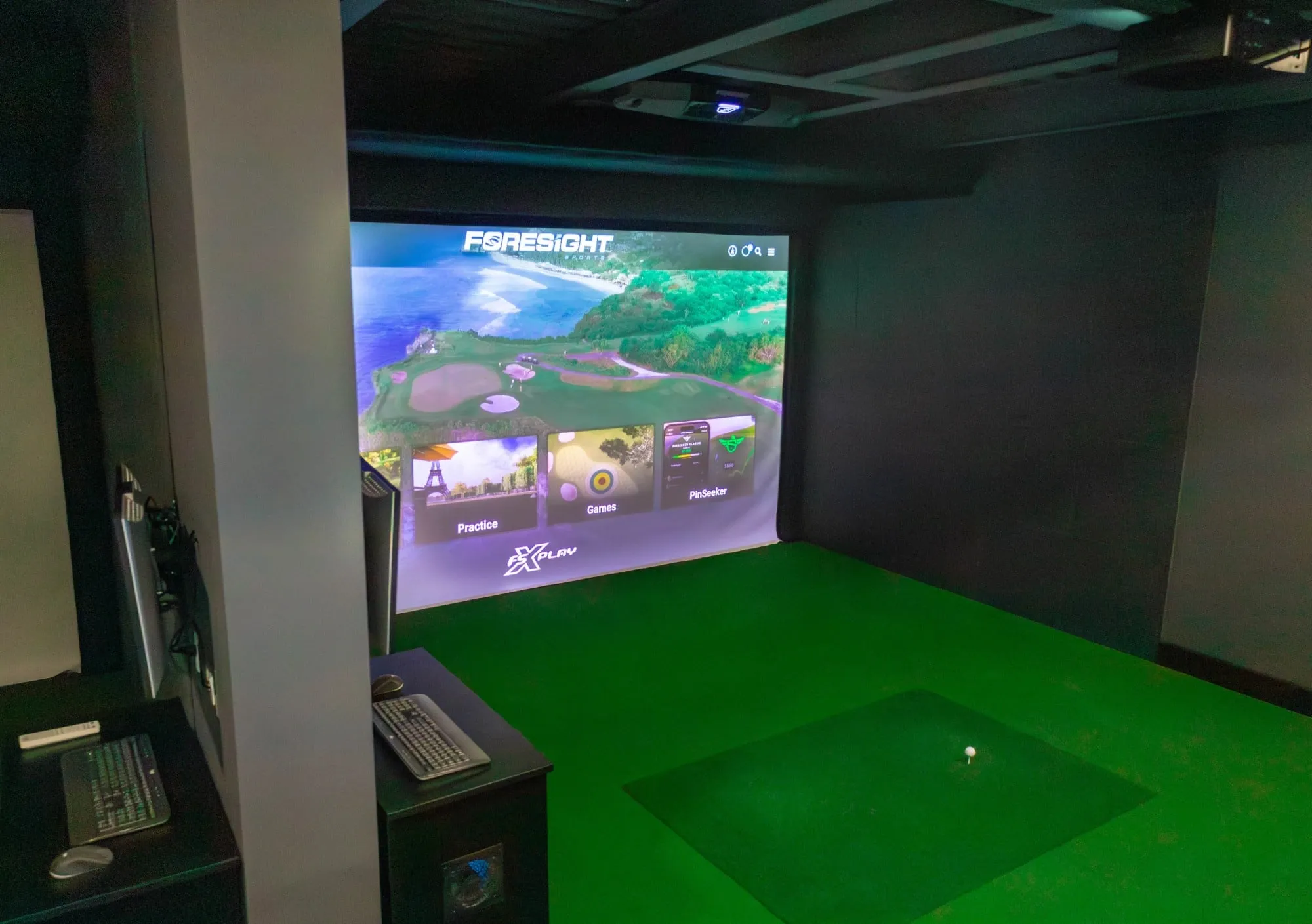 A golf simulator setup with a screen showing a golf course and a golf mat