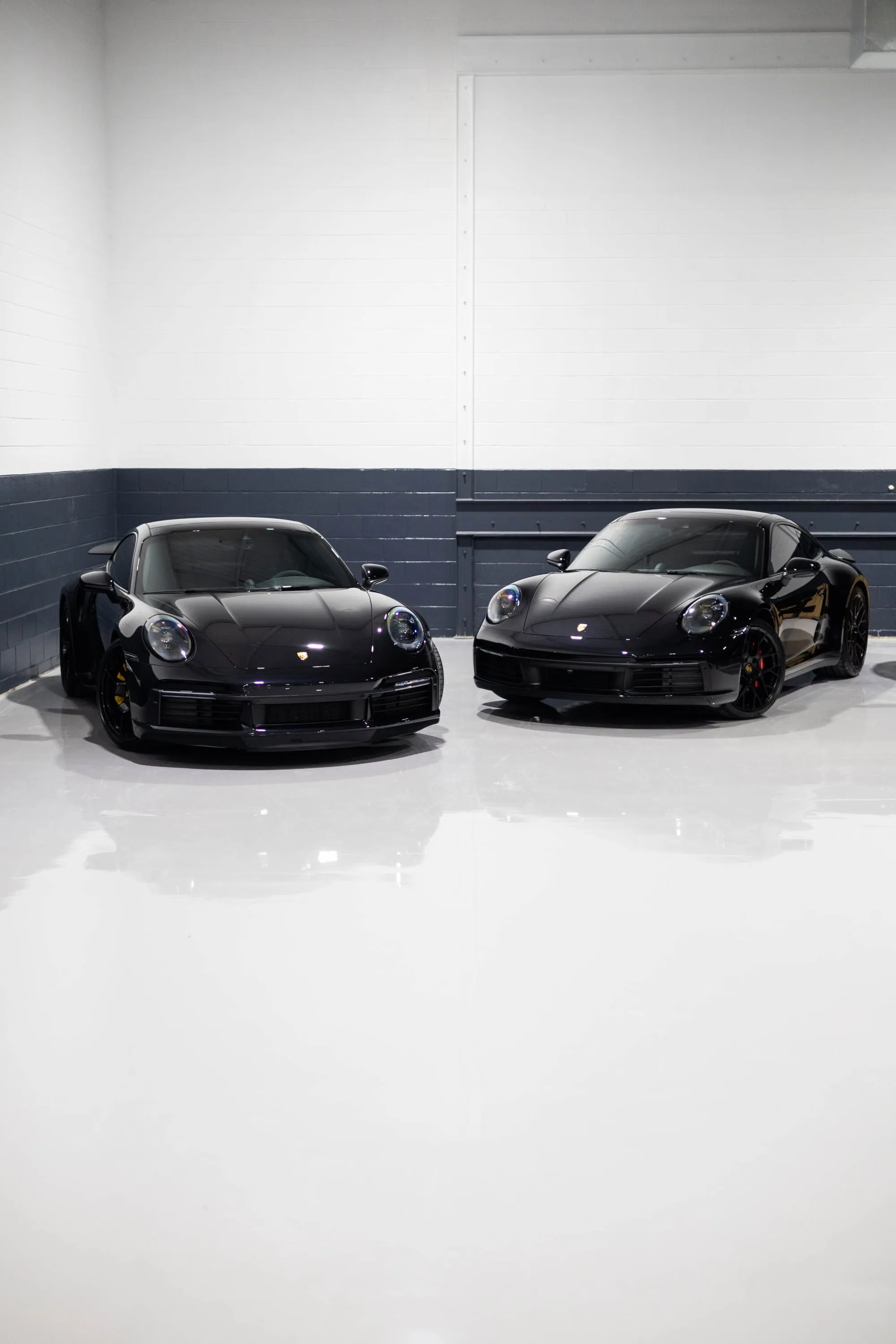 Two black cars parked in a garage