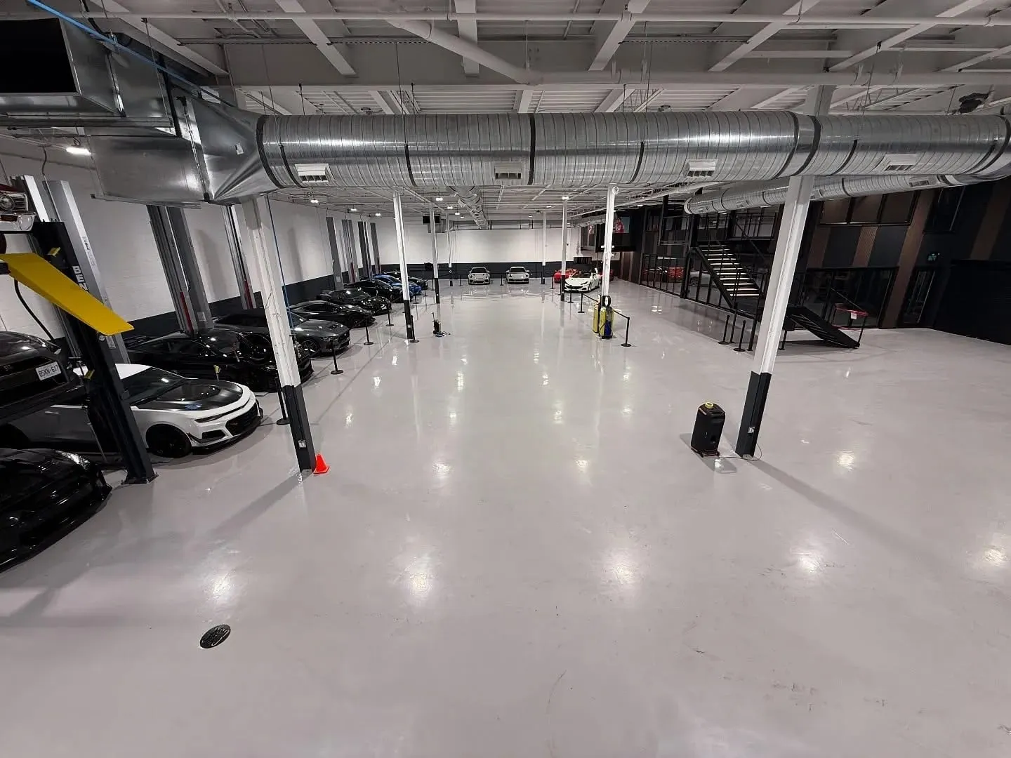 A brightly lit garage with lots of cars parked in it