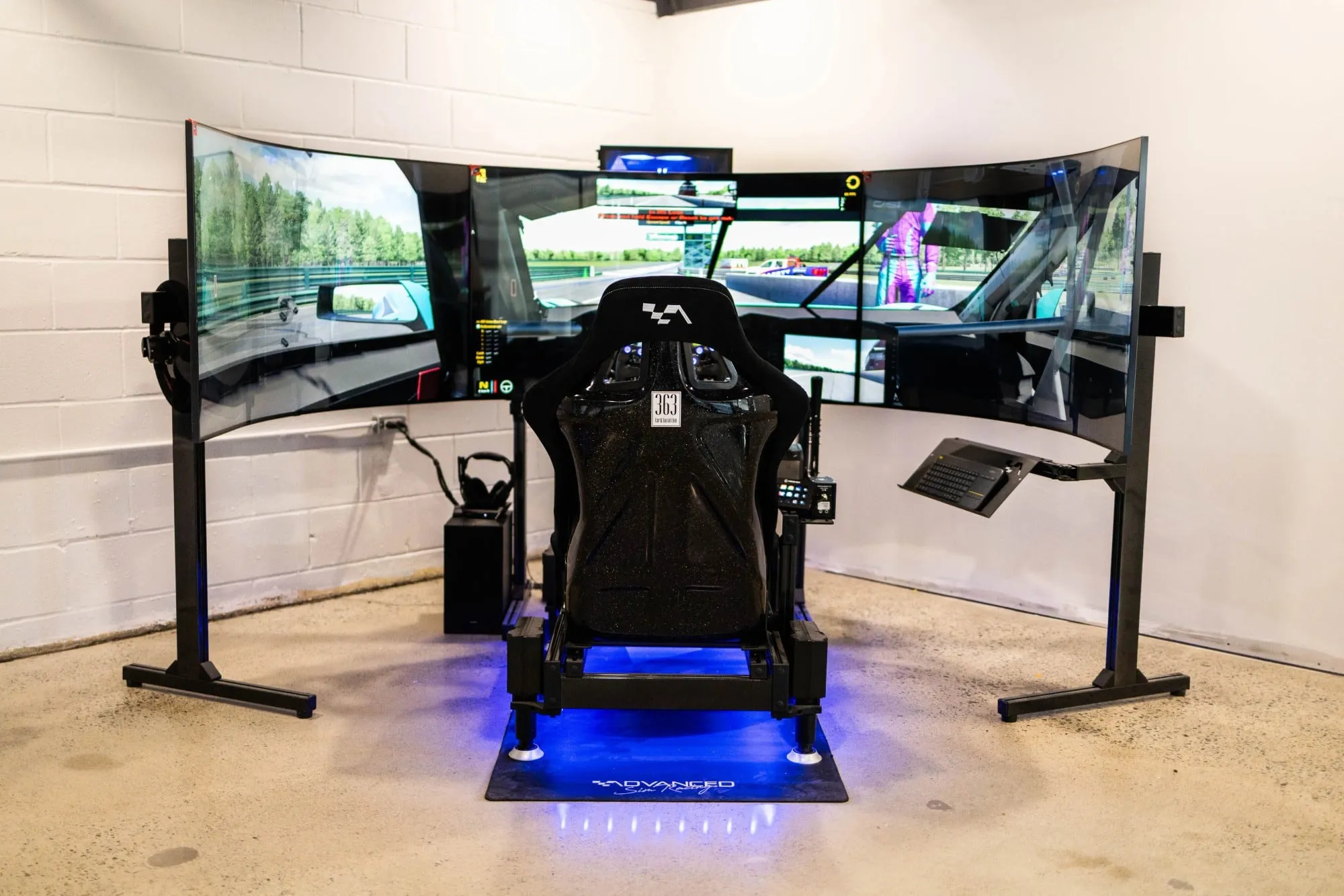 A racing simulator setup with three screens and a racing seat