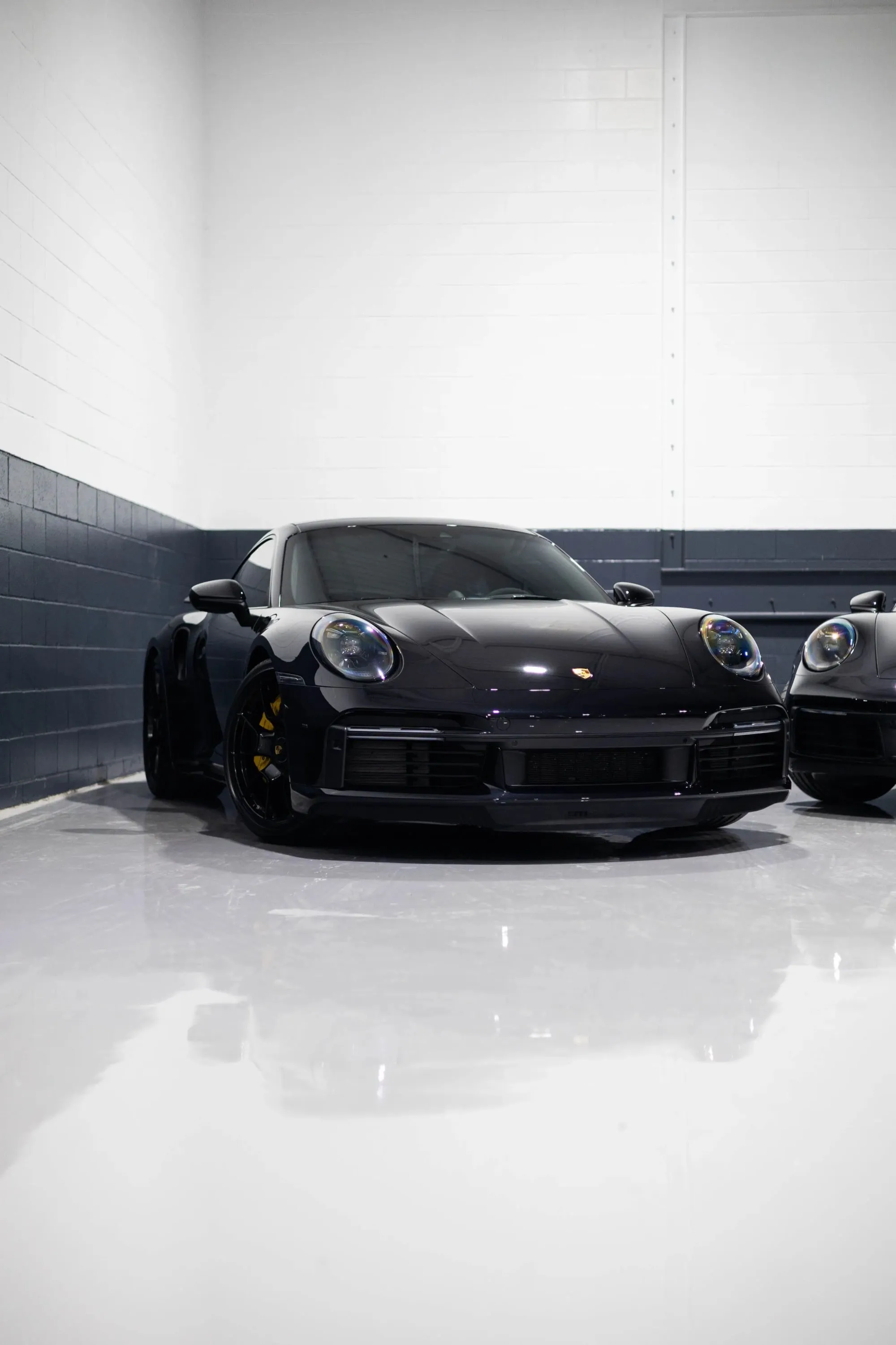 Two black porsches parked in a garage