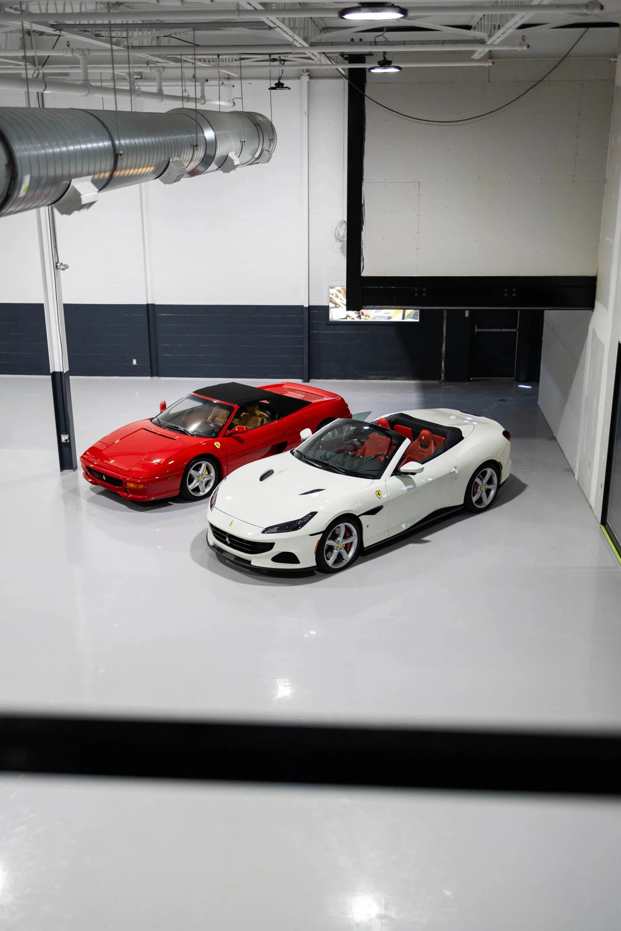 A red and white ferraris parked side-by-side in the showroom.