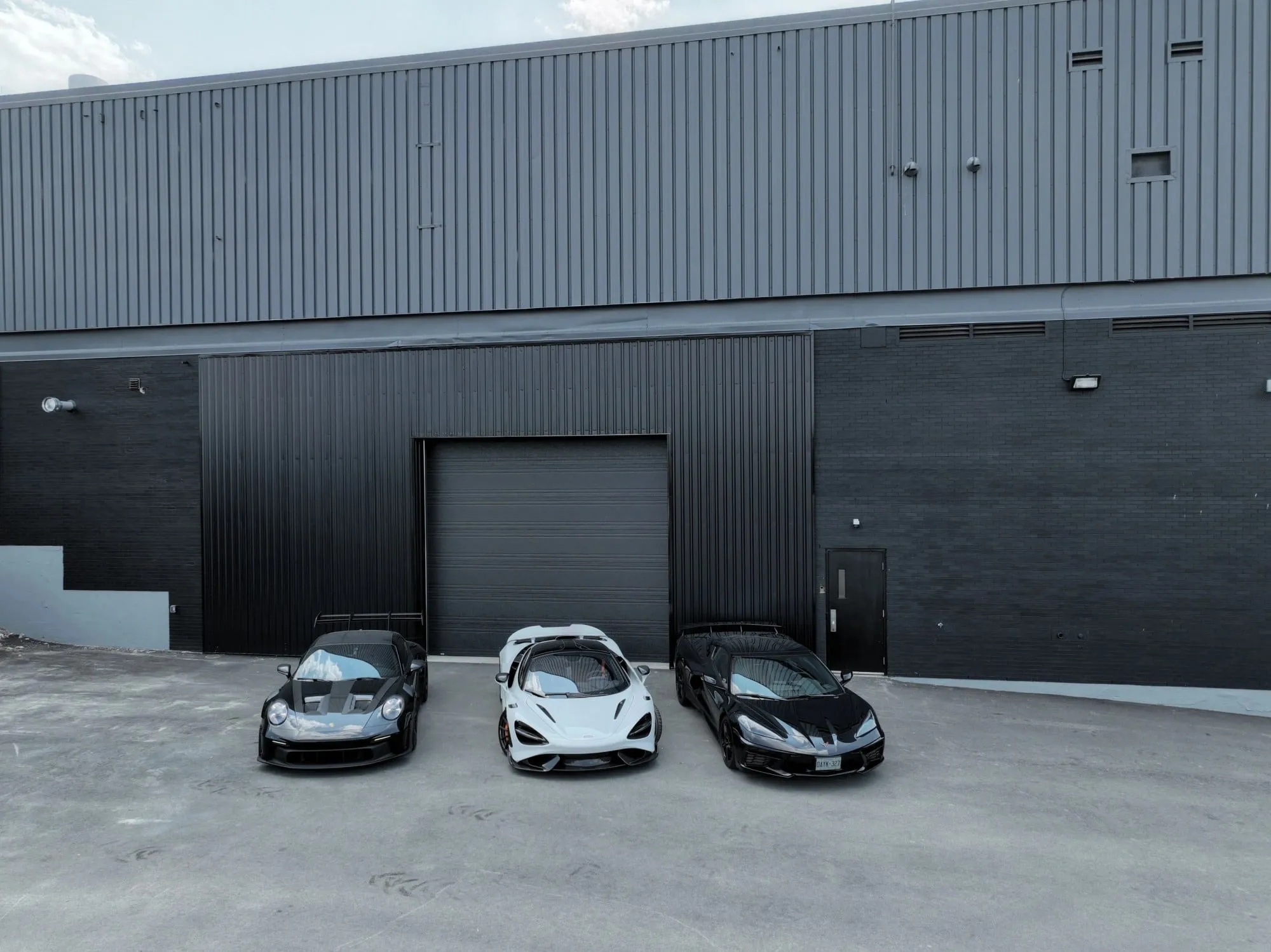 Three Mclaren cars parked in front of a building